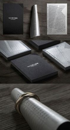 some black and white business cards on a wooden table with silver rings around them,