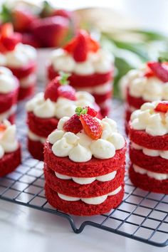 several red velvet cakes with white frosting and strawberries on top are sitting on a cooling rack