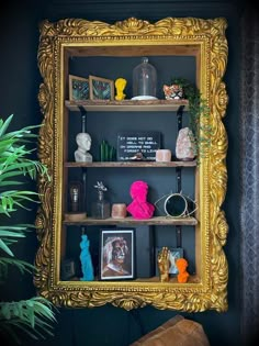 a gold framed shelf with pictures and other items on it