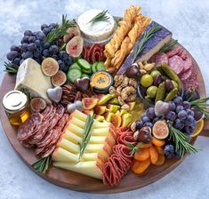 an assortment of cheeses, meats and vegetables on a platter with olives