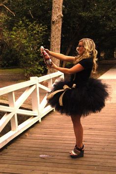 a woman in a black tutu holding a bottle