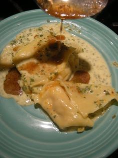 a blue plate topped with ravioli and sauce