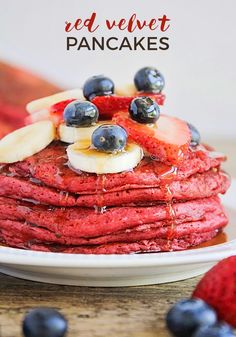 a stack of red velvet pancakes topped with bananas and blueberries