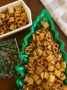 a green tray filled with cheetos next to a bowl of pretzels