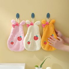 three pairs of oven mitts hanging on the wall