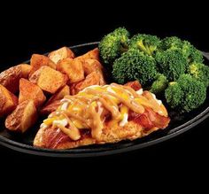 a black plate topped with chicken, broccoli and tater tot potatoes