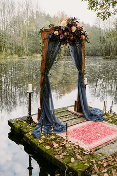 an outdoor ceremony setup with flowers and blue draping on the water's edge