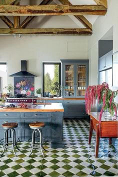 a kitchen with checkered flooring and an island in the middle, surrounded by two stools