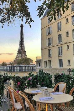 the eiffel tower is seen in the distance from an outdoor dining area with tables and chairs