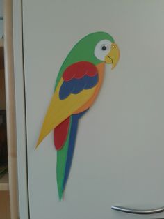 a green and yellow parrot is on the side of a refrigerator