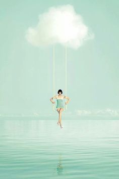 a woman is swinging on a rope in the water with a cloud above her head