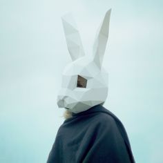 a person wearing a paper bunny mask on top of their head with the sky in the background