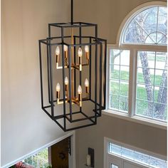 a chandelier hanging from the ceiling in a room with two windows and an open door