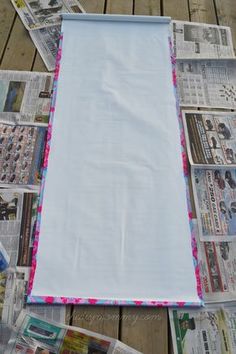 a pile of newspapers laying on top of a wooden floor next to a white sheet