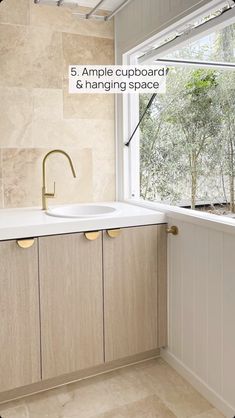 a white sink sitting under a window next to a wooden cabinet and counter top in a kitchen