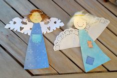 two paper angels sitting on top of a wooden table