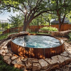 an outdoor hot tub in the middle of a yard with trees and rocks around it