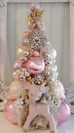 a pink and white christmas tree sitting on top of a table next to a mirror