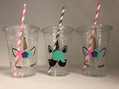 three plastic cups with unicorn faces and striped straws