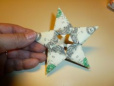 a person is holding an origami star with money on it