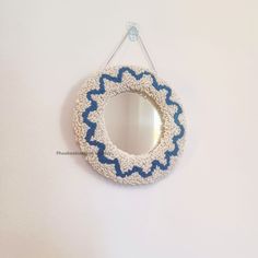 a white and blue wreath hanging on a wall with a mirror in the corner next to it