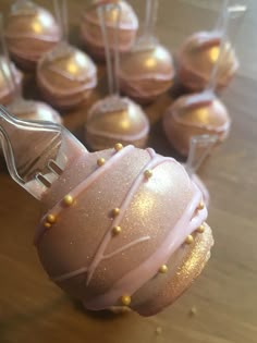 some pink and gold decorated desserts on a wooden table with forks in the foreground