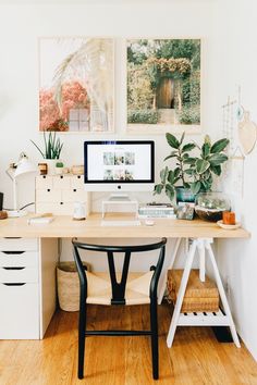 a desk with a computer on top of it next to some plants and other items