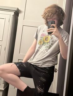 a young man taking a selfie in front of a mirror with his leg up