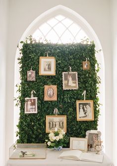 a table topped with pictures and flowers next to a wall covered in green ivys