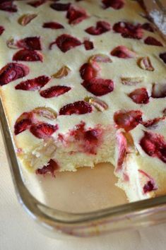 a close up of a cake in a pan with strawberries on the top and one slice missing