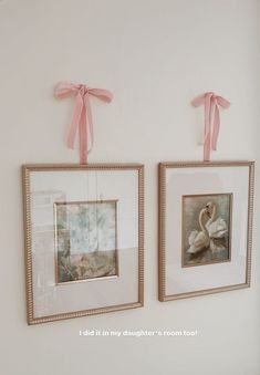 two framed pictures hang on the wall next to each other with pink ribbons around them