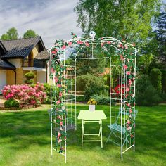 a garden with a table, chairs and a white gazebo in the middle of it