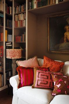 a living room filled with lots of bookshelves and pillows on top of a white couch