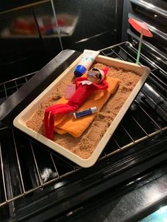 an elf laying in the oven next to some sand