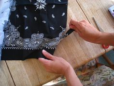 a person is cutting fabric with scissors on a wooden table next to a pair of scissors