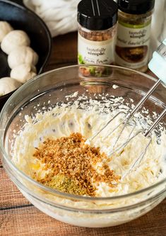 a bowl filled with mashed cauliflower and seasoning sitting on top of a wooden table