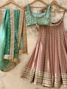 A three-piece chestnut brown and jade green zari lehenga set from the Priti Sahni collection. This beautiful georgette small butti chestnut brown lehenga with a heavy border of sequin, pearl and zari work detail with brown accent is paired with a raw silk green blouse with sequin and zardosi embroidery detail all over. The lehenga has side hanging ball tassels to the waistline. And the blouse has a sequins tassel tie-up at the back. This outfit is completed with a sequin tulle dupatta with jade Raw Silk Blouse, Jade Green Color, Pearl Work, Lehenga Designs Simple, Green Lehenga, Half Saree Designs, Indian Dresses Traditional, Traditional Indian Outfits, Party Wear Indian Dresses