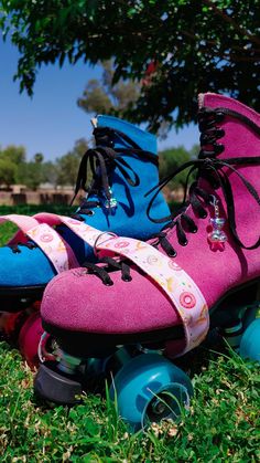 three roller skates are lined up in the grass with one blue and one pink