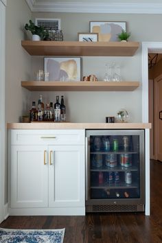 an open refrigerator in the corner of a kitchen with shelves above it and bottles on top