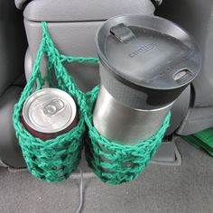 two cups are in the back seat of a car, one is holding a can