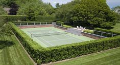 an aerial view of a tennis court surrounded by hedges