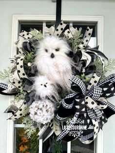 a white dog is hanging on a black and white deco mesh wreath with polka dots