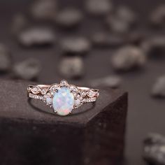 an opal and diamond ring sits on top of a rock