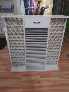 a white cabinet sitting on top of a hard wood floor next to a counter with pens and pencils