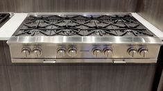 a stainless steel stove with four burners and two oven doors on the front side