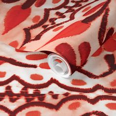 an orange and red pattern on a white background with a silver can in the foreground