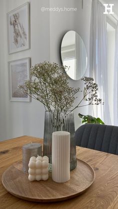 a wooden table topped with a vase filled with flowers next to a candle and mirror