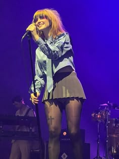 a woman standing in front of a microphone on stage