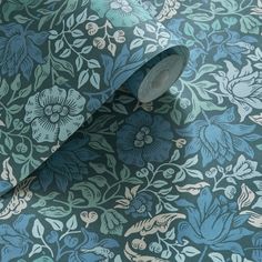 a blue and green wallpaper with floral designs on the side, along with a roll of tape