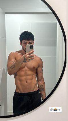 a shirtless man taking a selfie in front of a mirror with his cell phone